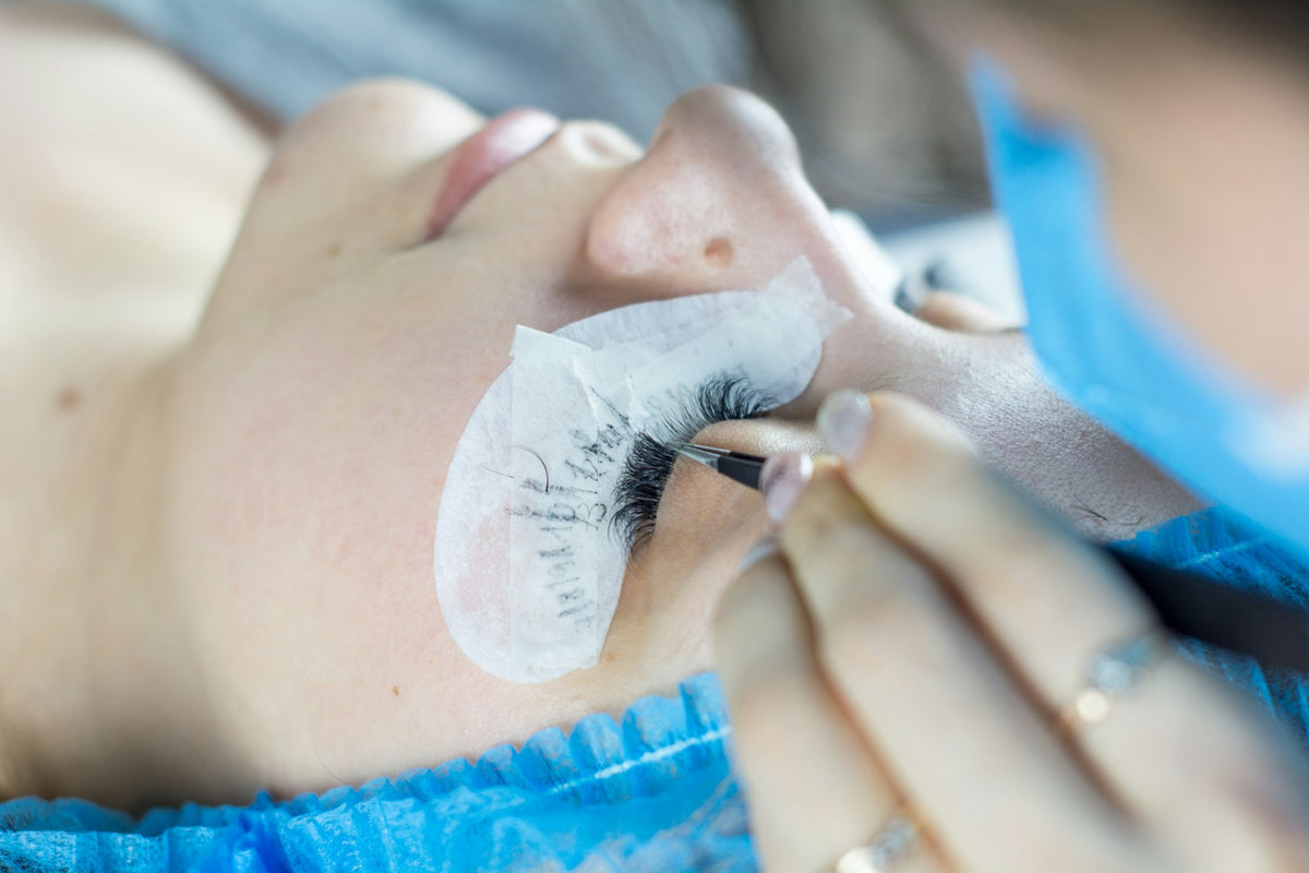 Technicienne posant des extensions de cils (photo d'ambiance)